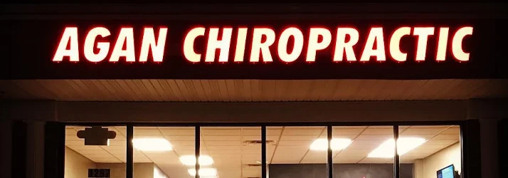 Illuminated storefront sign displaying the text “AGAN CHIROPRACTIC” above the entrance of a clinic.